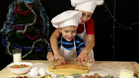 Two kids kneading the dough for xmas cookies together