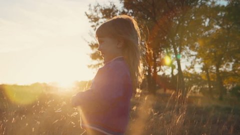 Little girl runs parallel to the sunset in the park. lens flare effect
