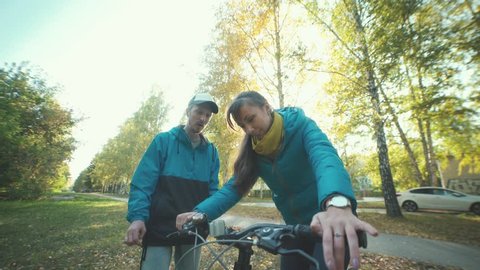 Man teaches girl to ride a bike. A young man wearing a cap showing a girl bike device. Bicycle brakes. Unusual date. Thoughtful man helping his girlfriend.
