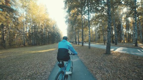 A bike. Cycling in the autumn park. A young man in a cap riding a bike and doing tricks. Biking in the autumn forest. Active leisure. Healthy lifestyle. Clear autumn day. Autumn leaves