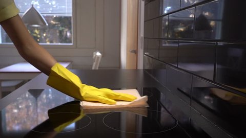 Housewife wipes the surface of the electric stove with a special cleaning cloth.  Slow motion. Dolly shot.
