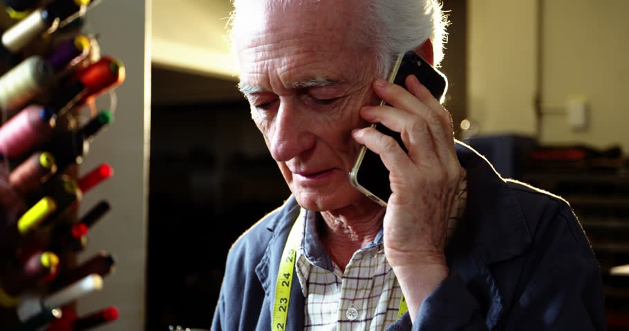Shoemaker talking on the mobile phone in workshop 4k