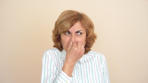 Woman holding her nose with her fingers because of bad smell