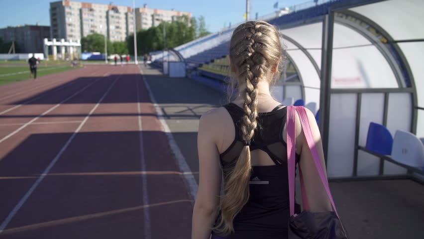 Young woman athlete goes through the stadium.