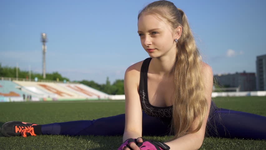 Young athlete woman sitting on twine in the stadium.