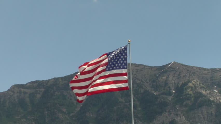 US flag on pole, with mountains behind it.
