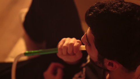 young bearded man smokes a hookah closeup