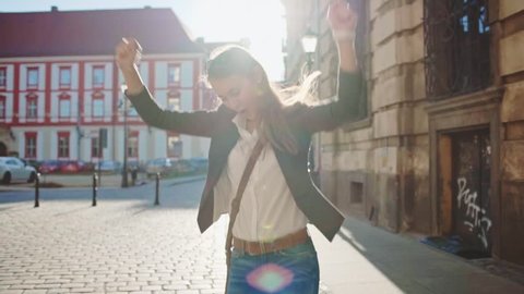 Happy Businesswoman Funky Dancing on the Sunny Morning City Street, Celebrating Success. SLOW MOTION. STEADICAM Stabilized Shot. Cheerful Business Woman Dancing Outdoors. Lens Flare.