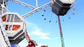 Fun fair Ferris wheel, attraction rides turning swinging against a bright blue sky in an amusement park, sunny outdoors. Recreational exciting activities, family day out. Machines in motion, exterior.