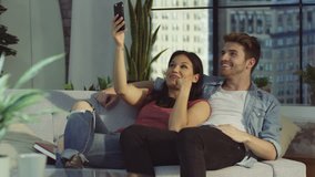 4K Affectionate couple relaxing at home & making video call on smartphone. Shot on RED Epic.