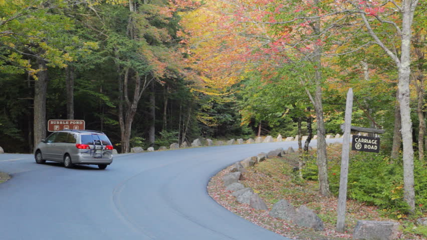 A man walking by the Carriage Road sign on Park Loop Road in Acadia National Park, Maine, in Autumn.