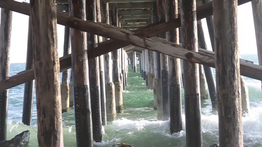 Waves smashing into supports of ocean dock.