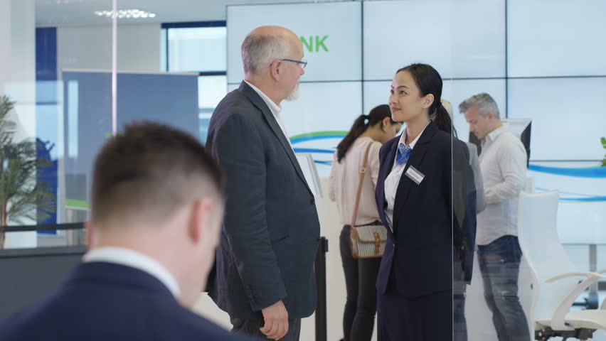 4K Modern city bank with customers & staff, 1 man assisting customer & getting signature on document. Shot on RED Epic. | Shutterstock HD Video #20321854