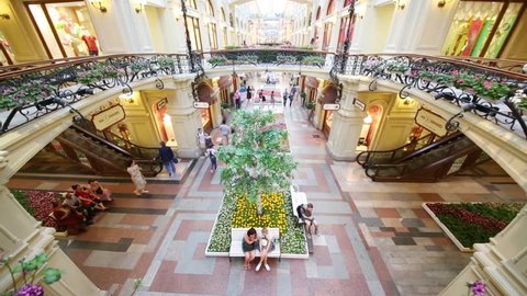 MOSCOW - JUL, 17, 2016: People sitting and walking near flowerbeds and escalators in multi-storey GUM on Red Square. Shoe brand New Balance has opened new shop in trading house GUM.
