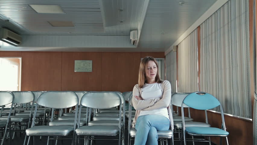 An attractive caucasian woman uses her new digital PC tablet with various hand gestures (scrolling, touching, typing) in the empty conference hall of cruise ship.