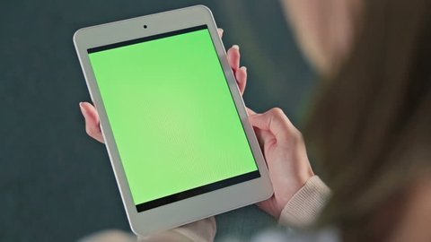 Woman looking at tablet with green screen. Close up shot of woman's hands with pad