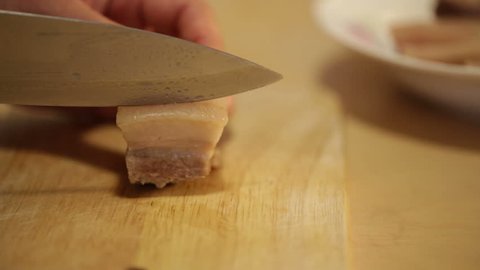 Asian cook cutting boiled pork into slices to prepare traditional soup