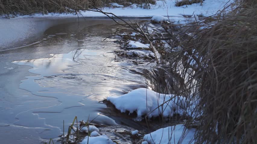 Small waterfall in a forest stream with ice on both hand in winter 
