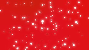 Festive Christmas background of sparkly white and yellow light particles moving across a red gradient backdrop.