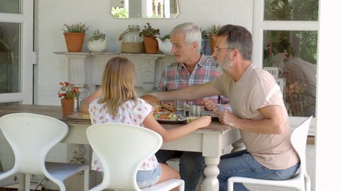 Same Sex Family At Home Eating Meal On Outdoor Verandah