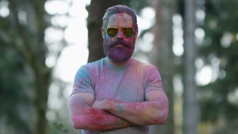 4K Portrait of serious hipster guy standing still while being covered in coloured powder at festival. Shot on RED Epic.