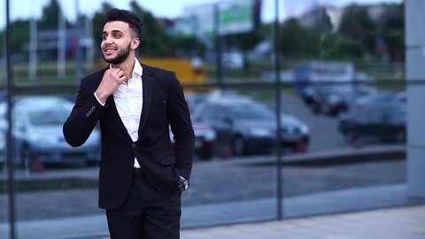 Young Handsome Businessman Arab Muslims is in the Business Center in Black Elegant Dress on Building Background. Businessman Man Male Shows Yes Succes Concept and Smiling