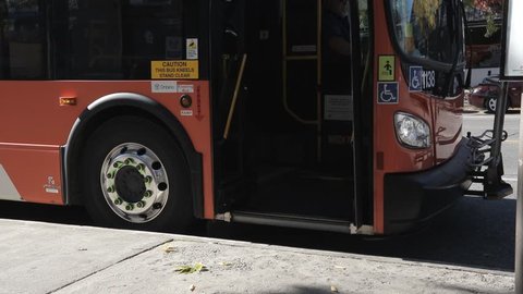 City bus closing doors and departing from bus stop.
