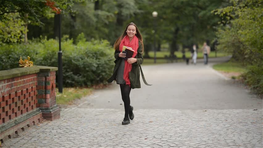 gorgeous beautiful happy woman walking in the autumn park, student girl talking on the telephone and smiling on a background of sunny autumn nature