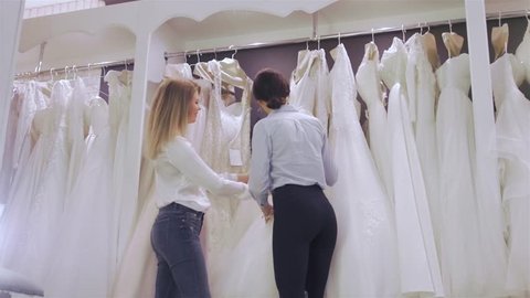 Smiling pretty bride chooses white gown at shop of wedding fashion. Happy Wed concept Stock Video