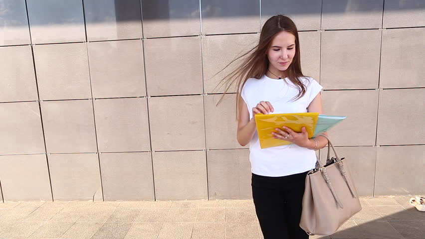 Female Work, Negotiating, Solves Problems, Walking to Camera Holds Document Talking on Smart Phone Indignant Displeased. Young Beautiful Business Woman Entrepreneur With Long Hair Wearing Suit