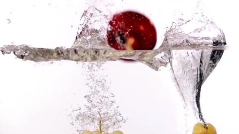 Pear apple grape falling into water on white background slow motion HD video. Water surface with floating whole fruits, splash bubbles and waves.