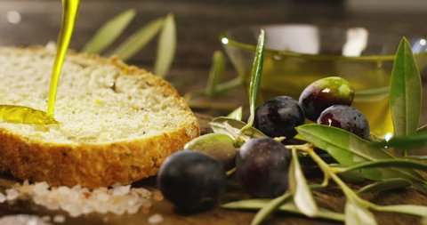 Genuine Italian organic oil cold pressed in slowmotion falls on organic bread. concept of nature and healthy food, healthy and natural. fresh olives and Tuscan Italian oil
