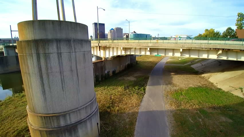 Morning aerial motion shot of downtown Dayton, Ohio USA.  The camera moves up the side of a tower, and chases birds from it. Buildings, bridges, bike path, and a river can be seen.