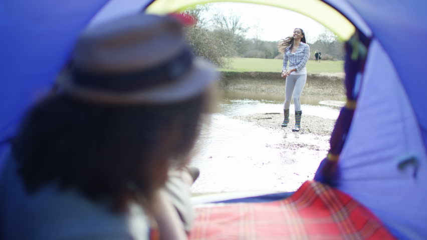 4K Young hipster guy watching his girlfriend from his tent on camping trip & then she comes to join him. Shot on RED Epic. Royalty-Free Stock Footage #20370952