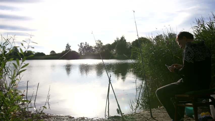 fisherman catches a fish and use the phone