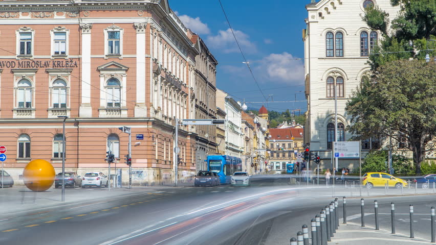 Street near new building of Croatian Music Academy timelapse in Zagreb, Croatia. Traffic on the road with trams, blue cloudy sky at sunny day