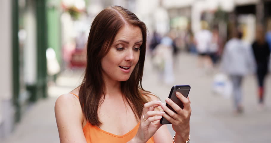 4k Young woman playing GO on her mobile phone in a city.