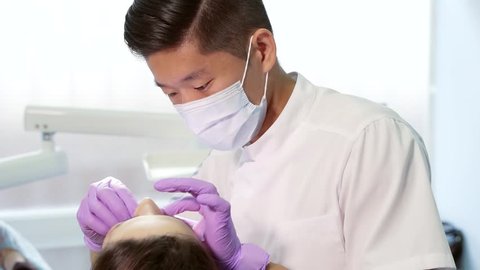Dentist Asian treats the patient in the office. Cosmetic dentistry is the veneers. 