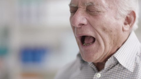 4K Close up portrait of elderly man sneezing in a chemist shop. Shot on RED Epic.