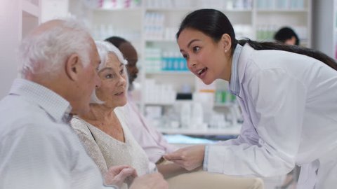 4K Friendly pharmacy worker gives prescription medication to customer in waiting area. Shot on RED Epic.