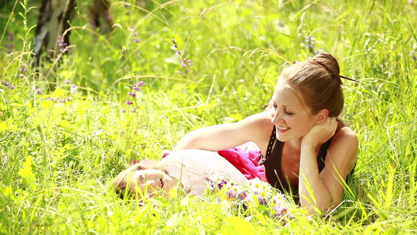 Mother and daughter lying in the grass. Looking at camera.