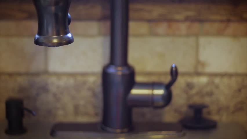 A man turns a water faucet on and off in the kitchen.