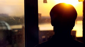 Silhouette of man listening to music from a smart phone with headphones on the sunset city background. 3840x2160