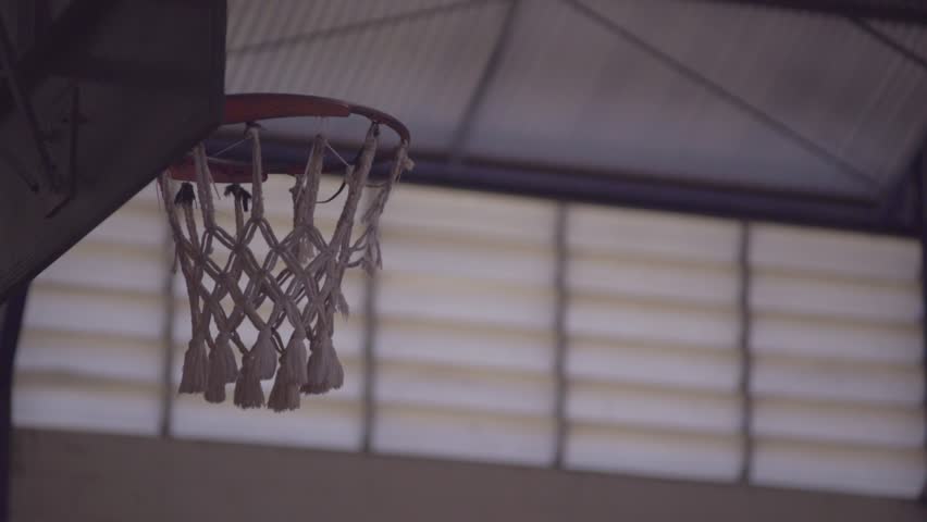 Basketball going through the basket at a sports arena - Large basketball arena with copy space