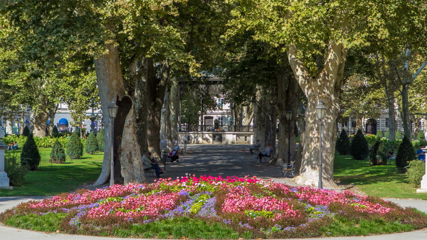 People around pavillion in Zrinjevac park timelapse in Zagreb, Croatia. Zrinjevac is spread over 12540 sq meters in city center. Flowerbed on foreground