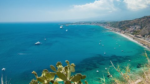 Scenic Taormina Sicily Italy Mediterranean Sea Overlook with Boats and a Cruise Ship in the Clear Blue Water Bay and Green Hillside Flora in the Foreground