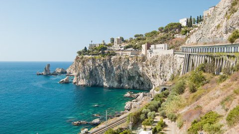 Taormina Sicily Coast Against Steep Cliffs with Passing Train on Railroad Against Blue Mediterranean Sea Water on a Sunny Summers Day in Italy