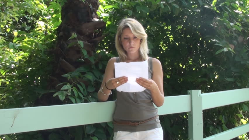 Young blonde woman reading a letter and getting upset