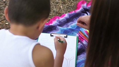Young mother with her son drawing in the Park their home
