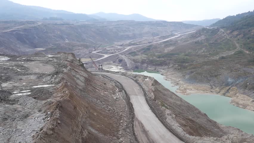 Aerial view on bucket wheel excavator and big dump truck in coal mine.
